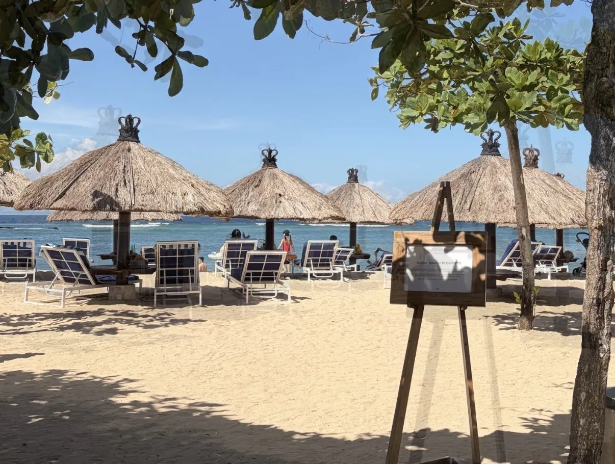Thatched beach umbrellas and navy-and-white loungers on the sand in front of the sea