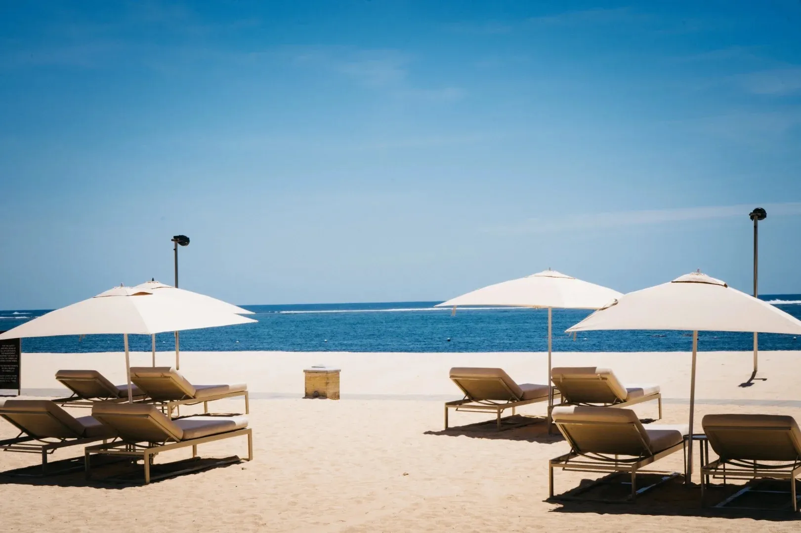 Sun loungers and white umbrellas on the sand facing the sea