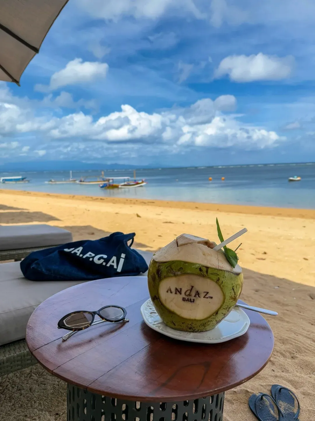 A fresh coconut carved with the Andaz name on a side table on the beach, with the sea behind
