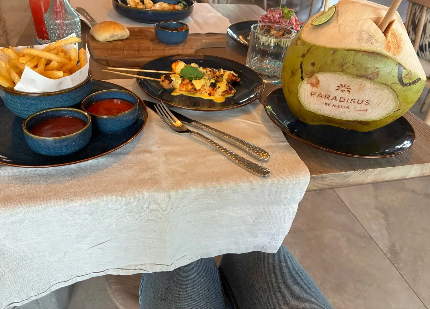 Dinner plates, fries, sambal and a branded coconut on a table