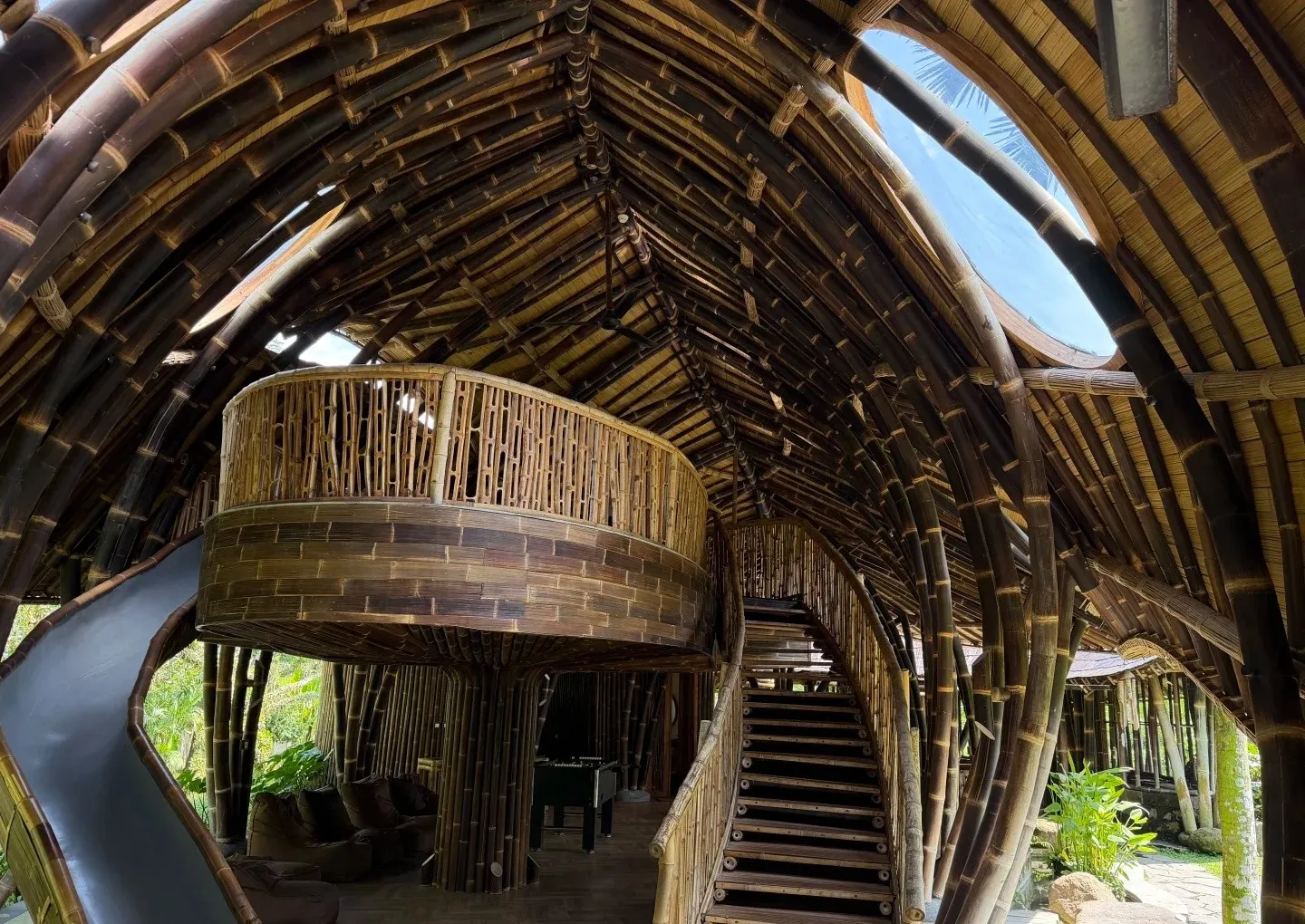 Inside a woven bamboo dining cocoon at Kubu, with a spiral stair and curved bamboo ribs