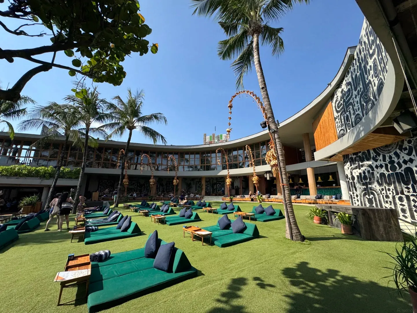 Green beanbags across the lawn in front of the curved beach club building and its patterned facade