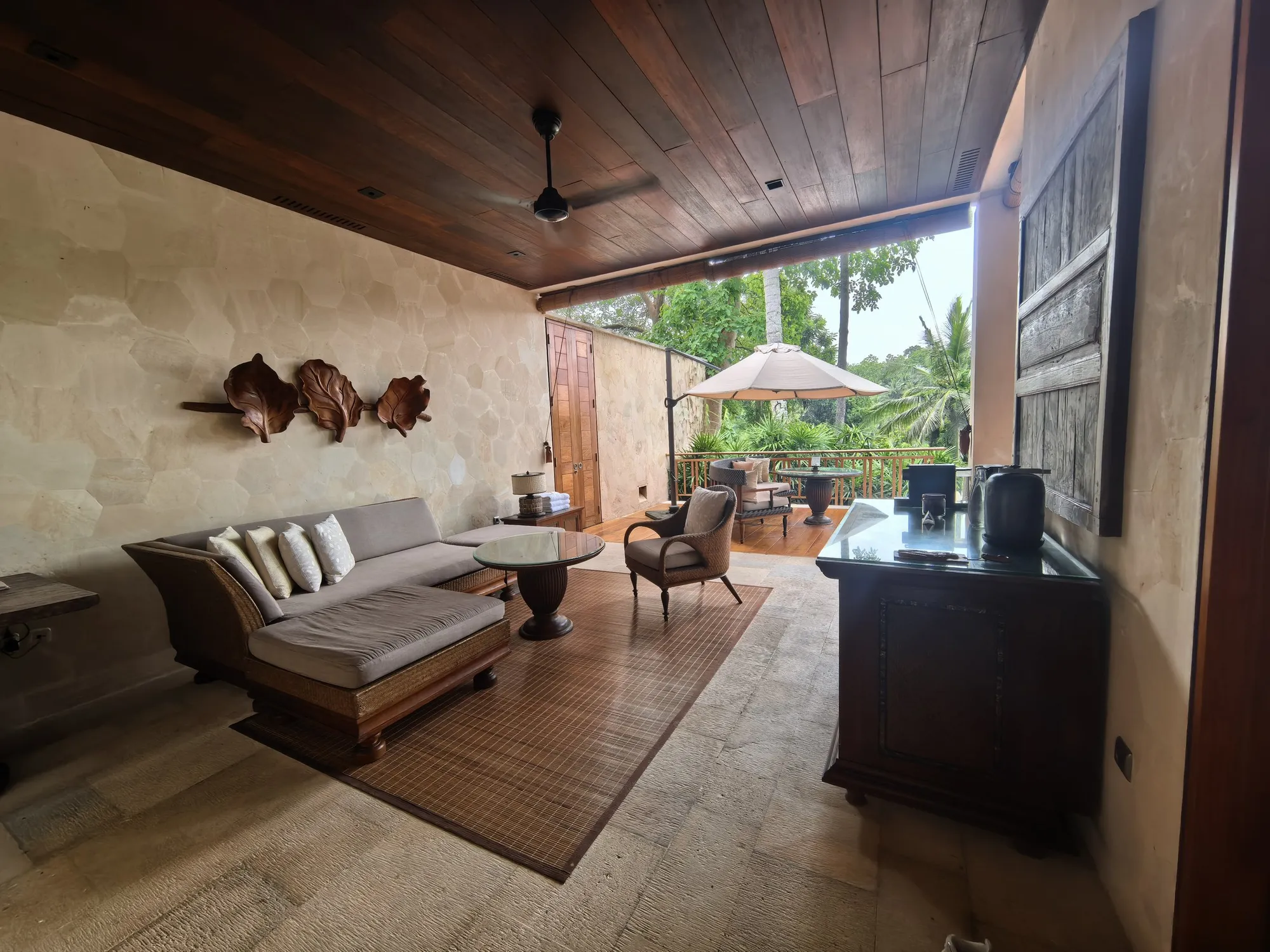 A suite living room with a daybed sofa and a desk, opening onto a covered terrace