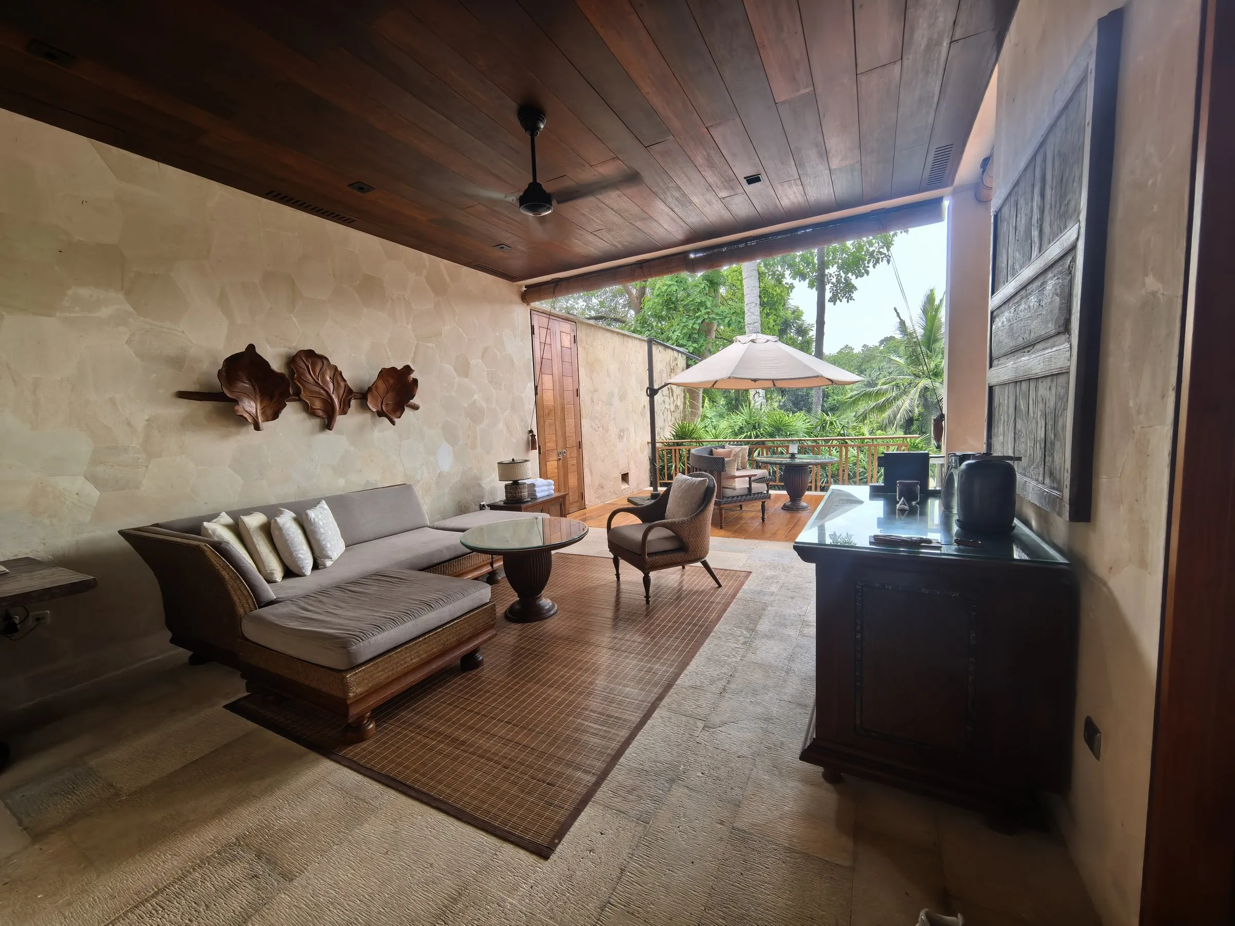 A suite living room with a daybed sofa and a desk, opening onto a covered terrace