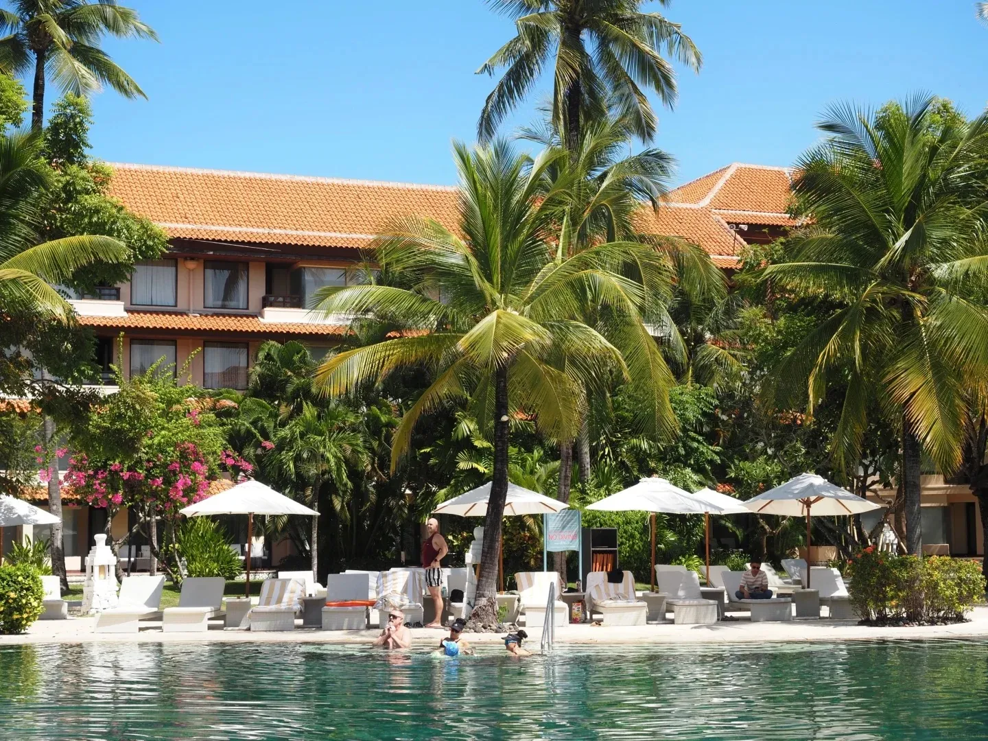 The main pool with sun loungers and umbrellas in front of a guest wing