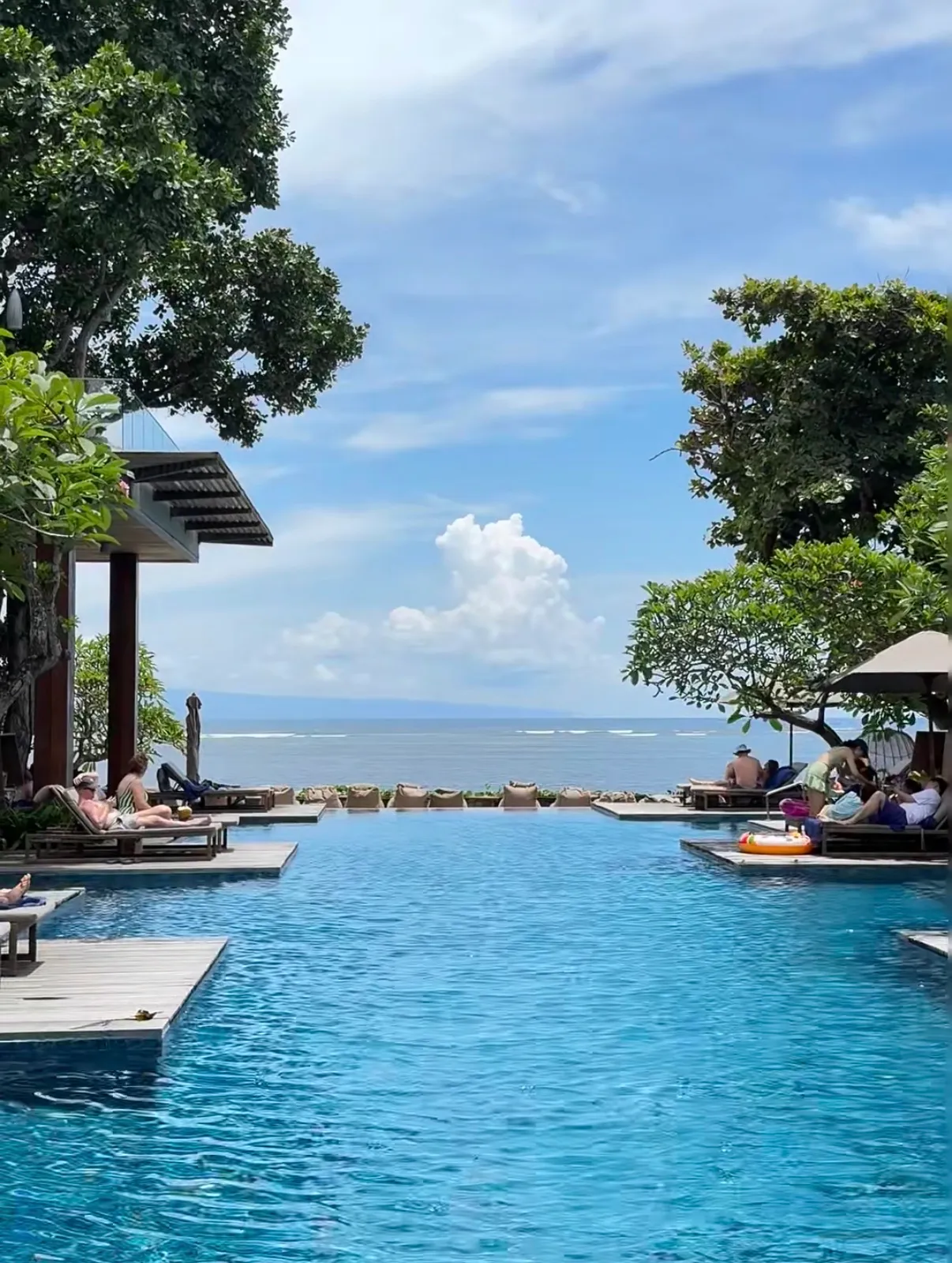The infinity pool running out towards the sea, with loungers on timber decks set into the water