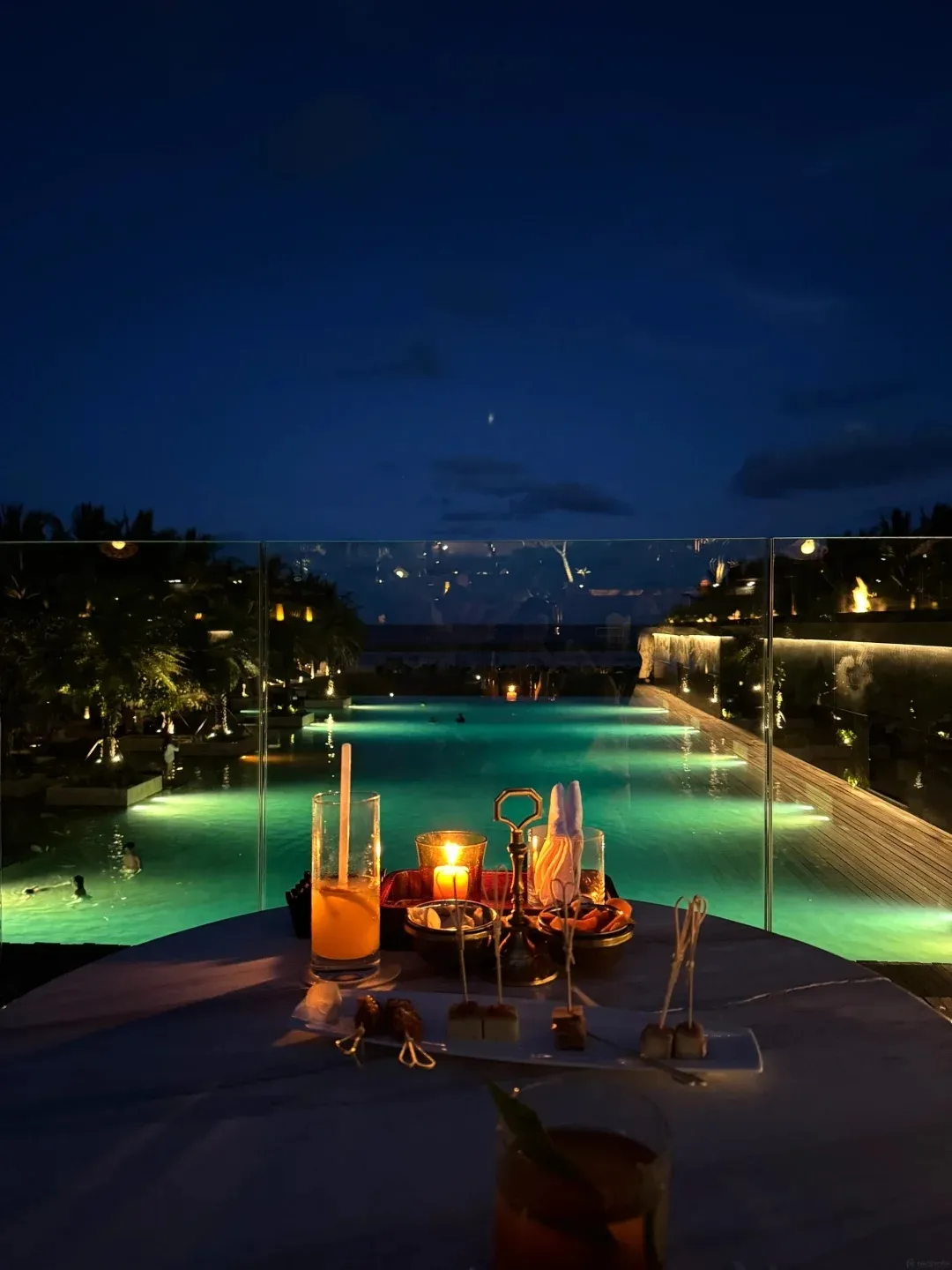 A candlelit table set above the lit pools at night