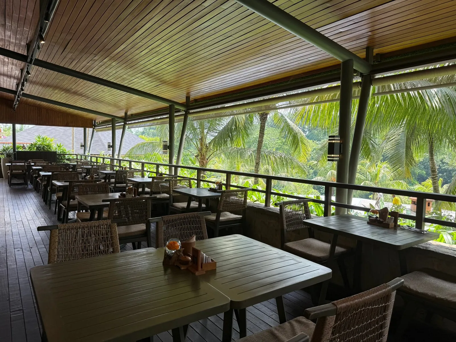 The restaurant’s open-air terrace, with timber tables and a view over the palm trees