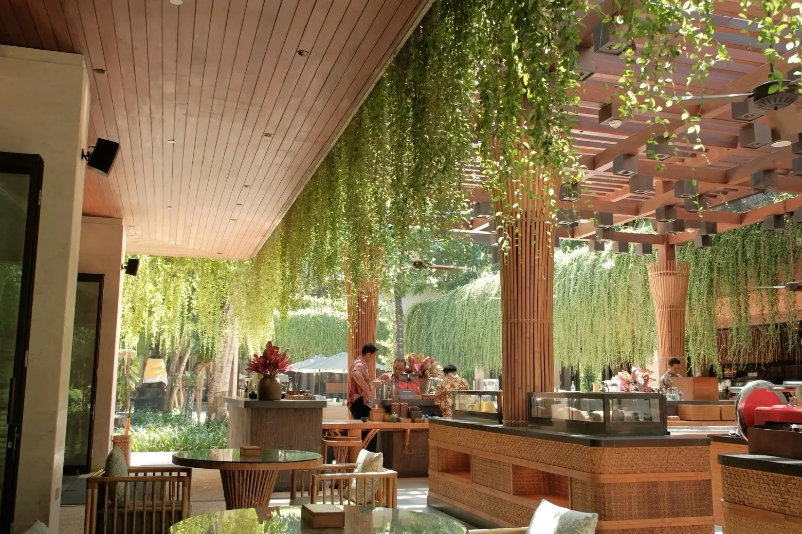 An open-air restaurant under hanging curtains of vines and bamboo-wrapped columns