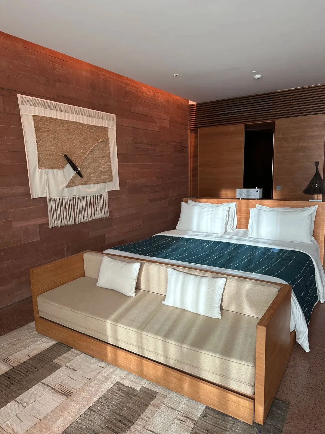 A Potato Head room with a woven wall hanging over the bed, a daybed sofa and warm timber walls