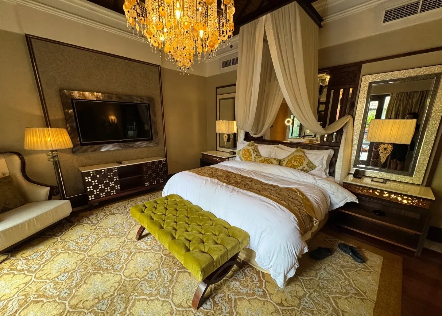 A St. Regis villa bedroom with a canopy bed under a crystal chandelier