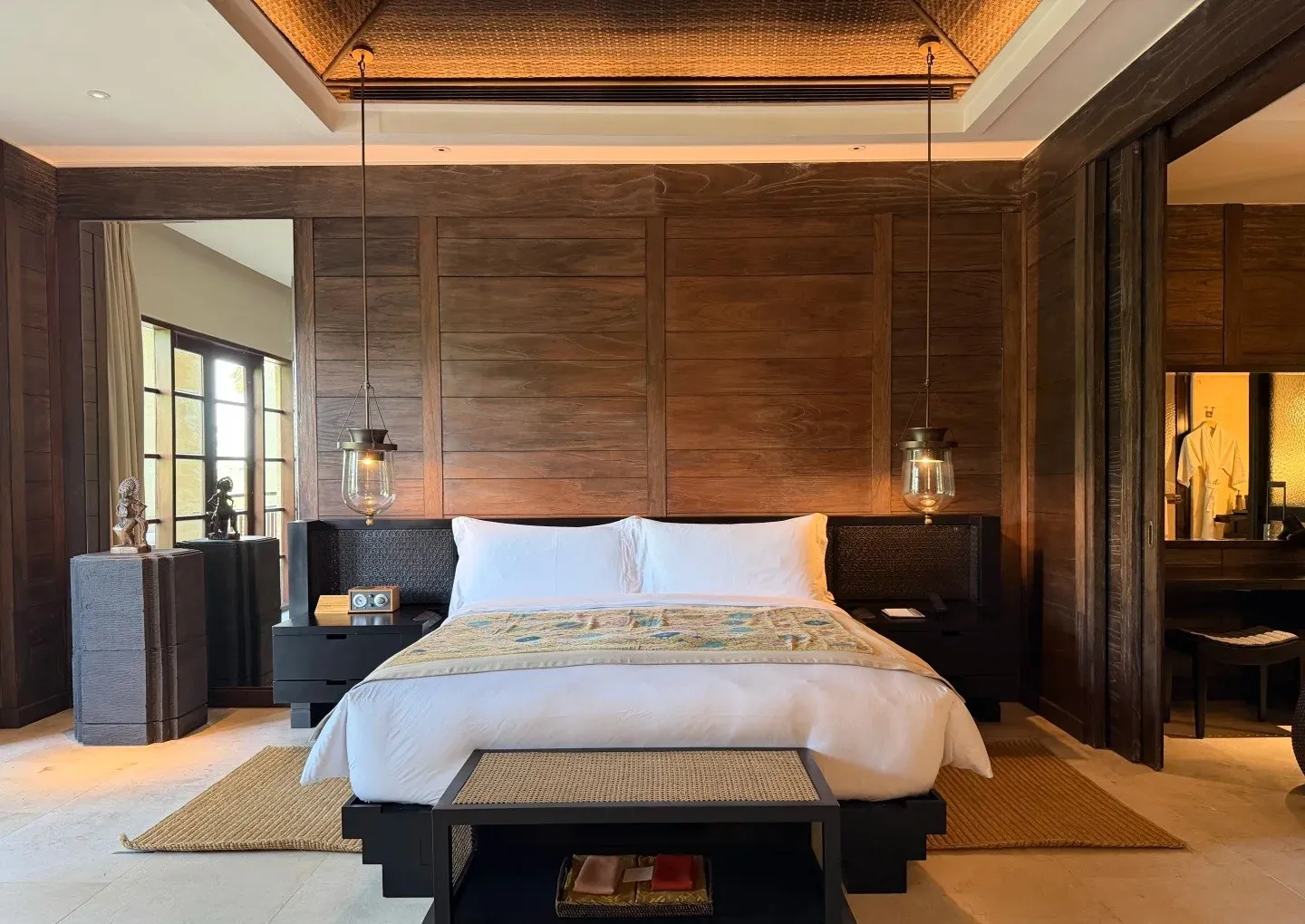 A Mandapa bedroom with a king bed, dark timber walls and tall windows on both sides