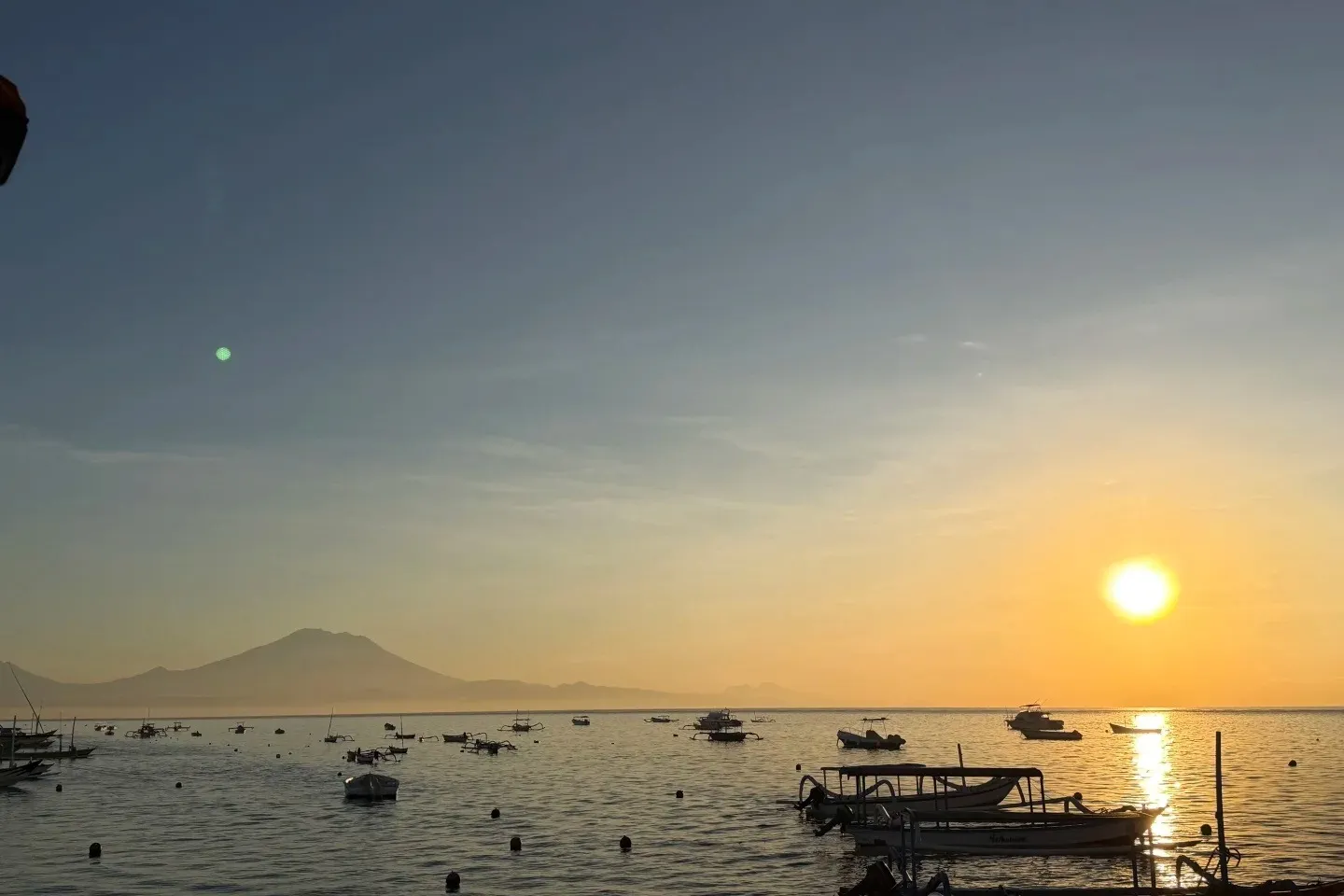 Sunrise over the sea from Sanur beach, with fishing boats and Mount Agung on the horizon