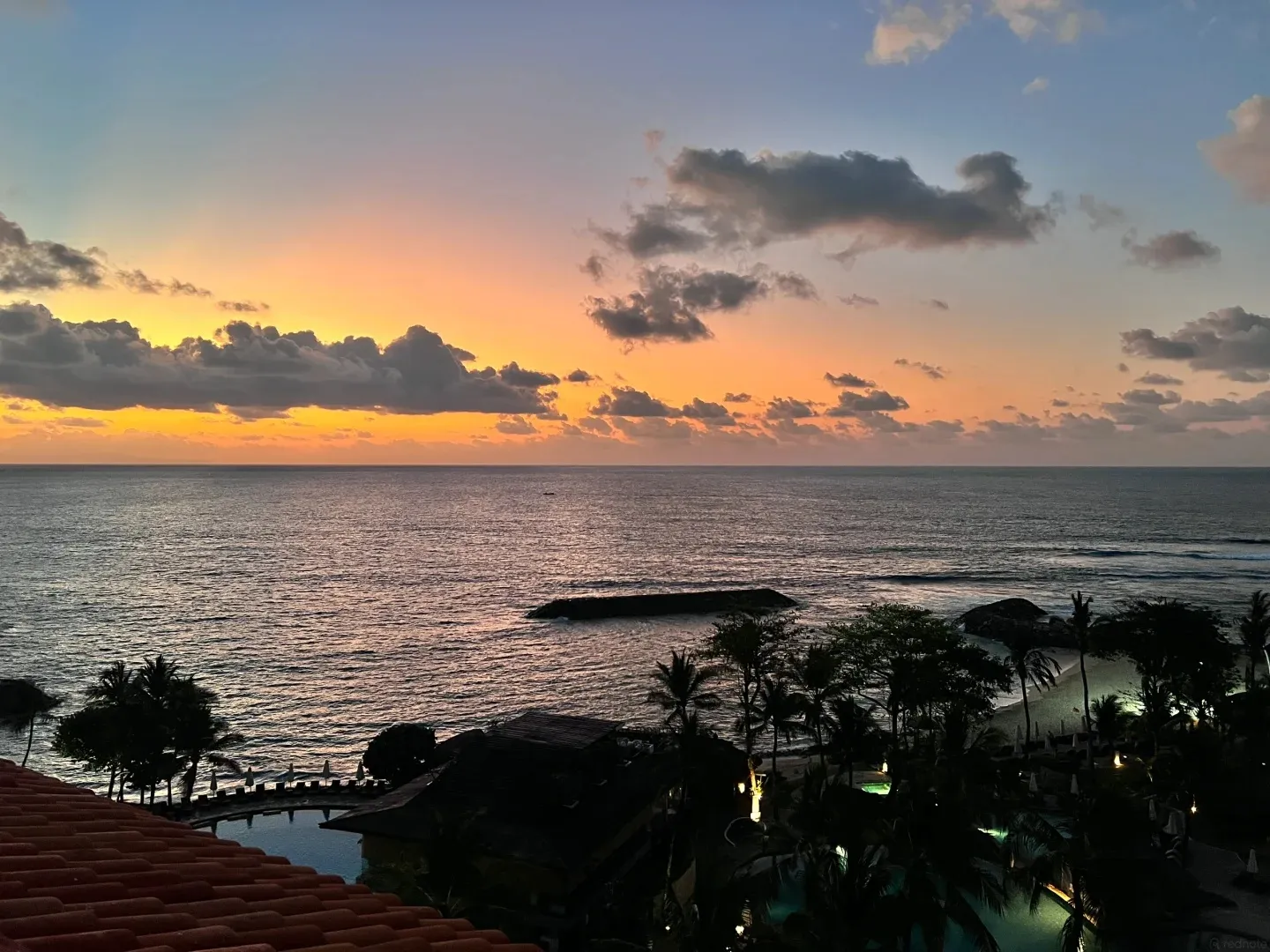 Sunset over the sea above the resort’s palm trees