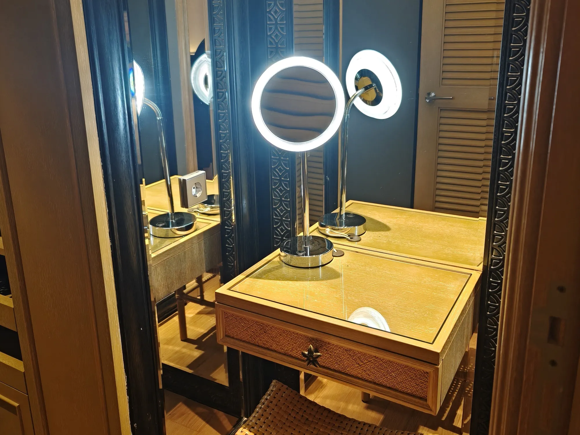 A dressing table with a lit magnifying mirror, a rattan stool and a full-length mirror